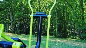 An outdoor exercise machine in a grassy area with trees in the background.