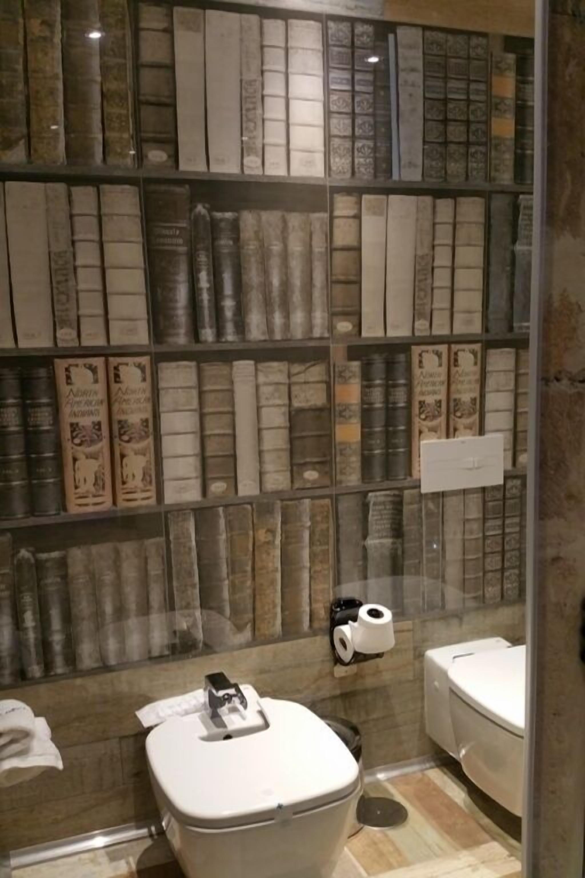 Un baño con una pared de azulejos únicos, un inodoro y un bidé.