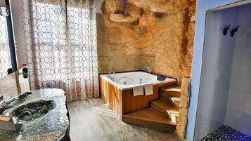 A modern bathroom with a freestanding bathtub, a glass-enclosed shower, and a stone wall.