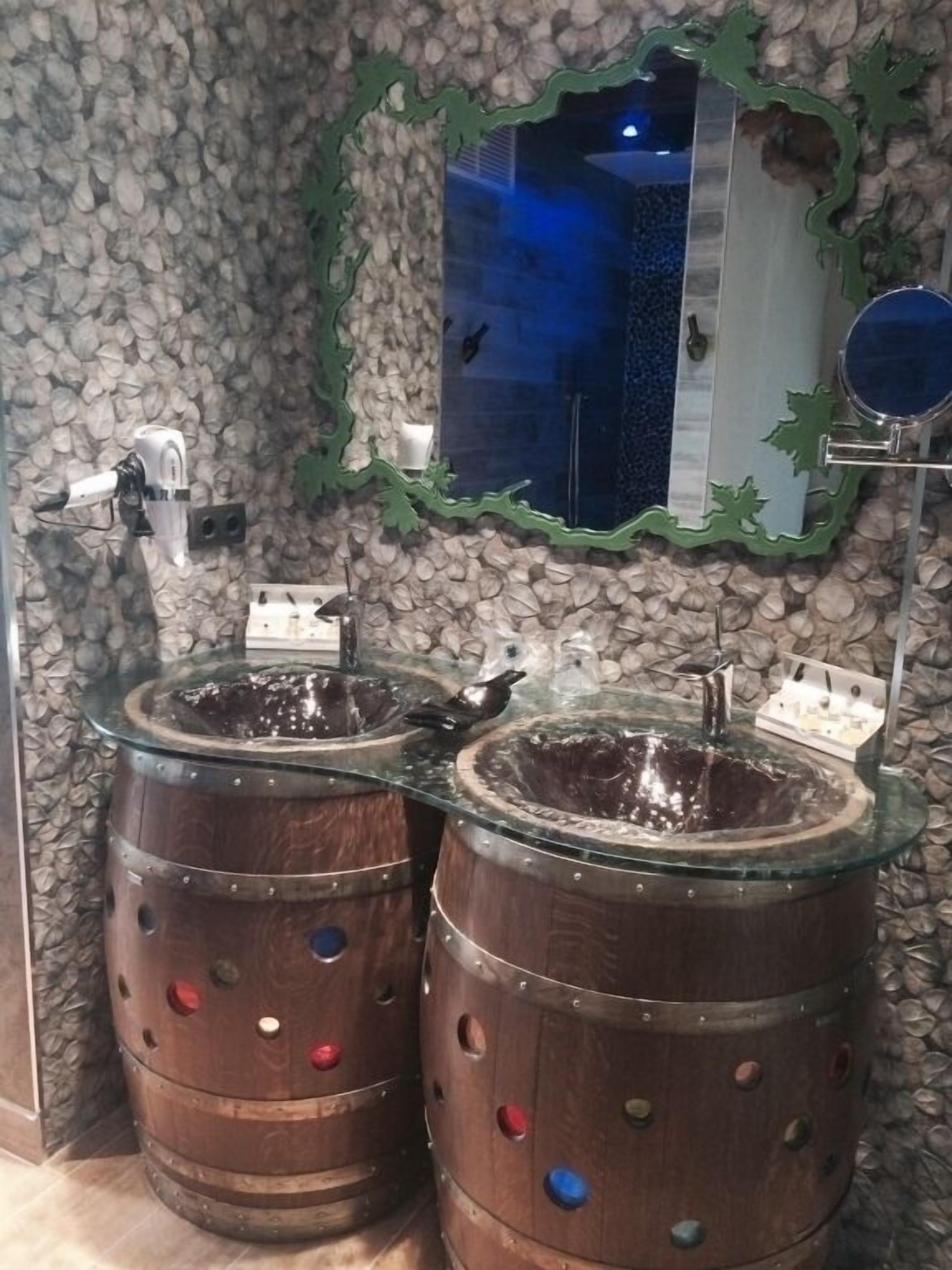 A bathroom with two wooden barrel sinks and a mirror with a green frame.