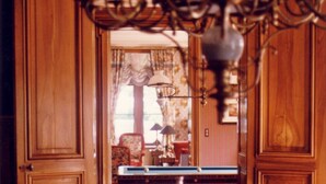 A wooden dining room with a chandelier, a pool table, and a blue upholstered chair. - Château Lagrave Béchade (Baleyssagues)