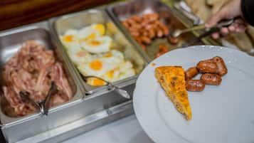 A buffet with various food options including meats, eggs, and sausages.
