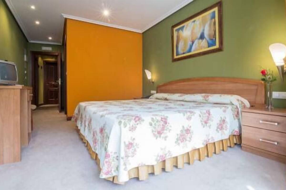 A bedroom with a bed, a dresser, a nightstand, and a painting on the wall.