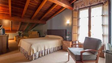 Un dormitorio con cama, una silla, un escritorio, una lámpara y una ventana con cortinas.