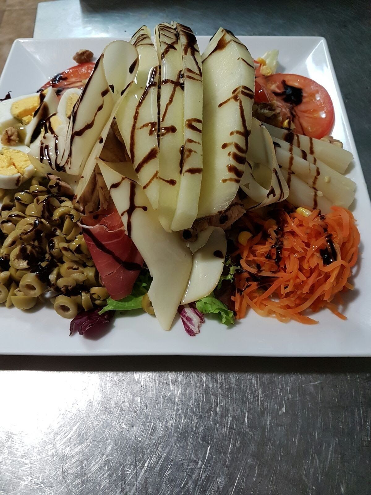 Une assiette remplie de différents aliments, notamment des tranches de bananes, une tomate, une salade et un œuf dur.