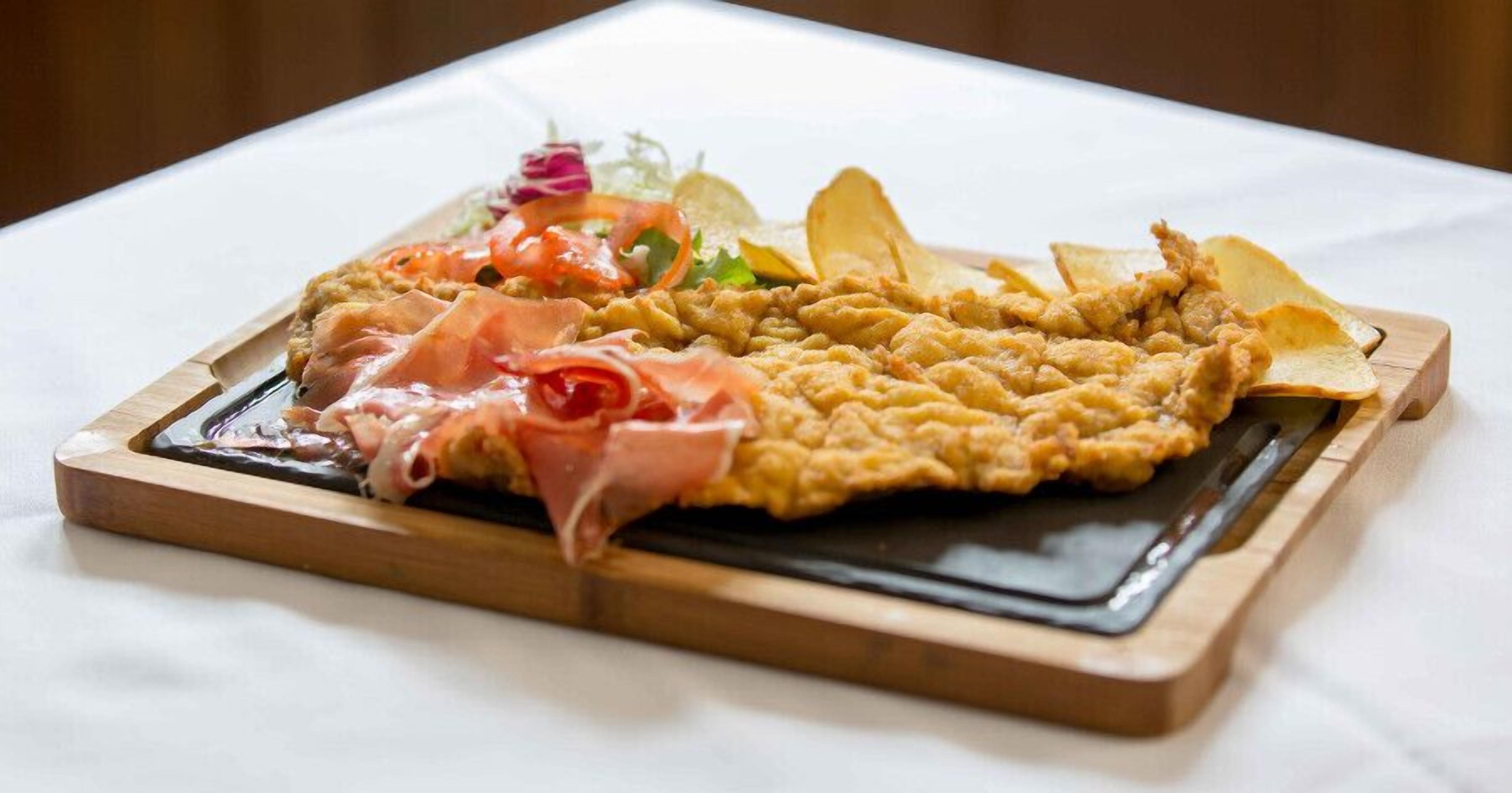 Een houten serveerplank met diverse gerechten, waaronder een visgerecht, vleesgerecht en friet.
