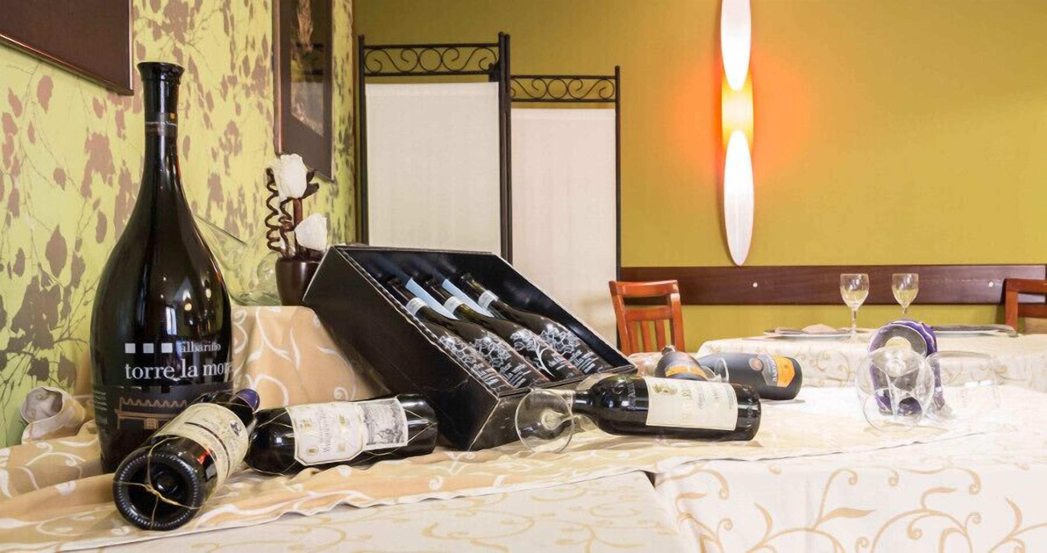 A hotel room with a bed, a bottle of wine, a wine box, and a candle on the table.
