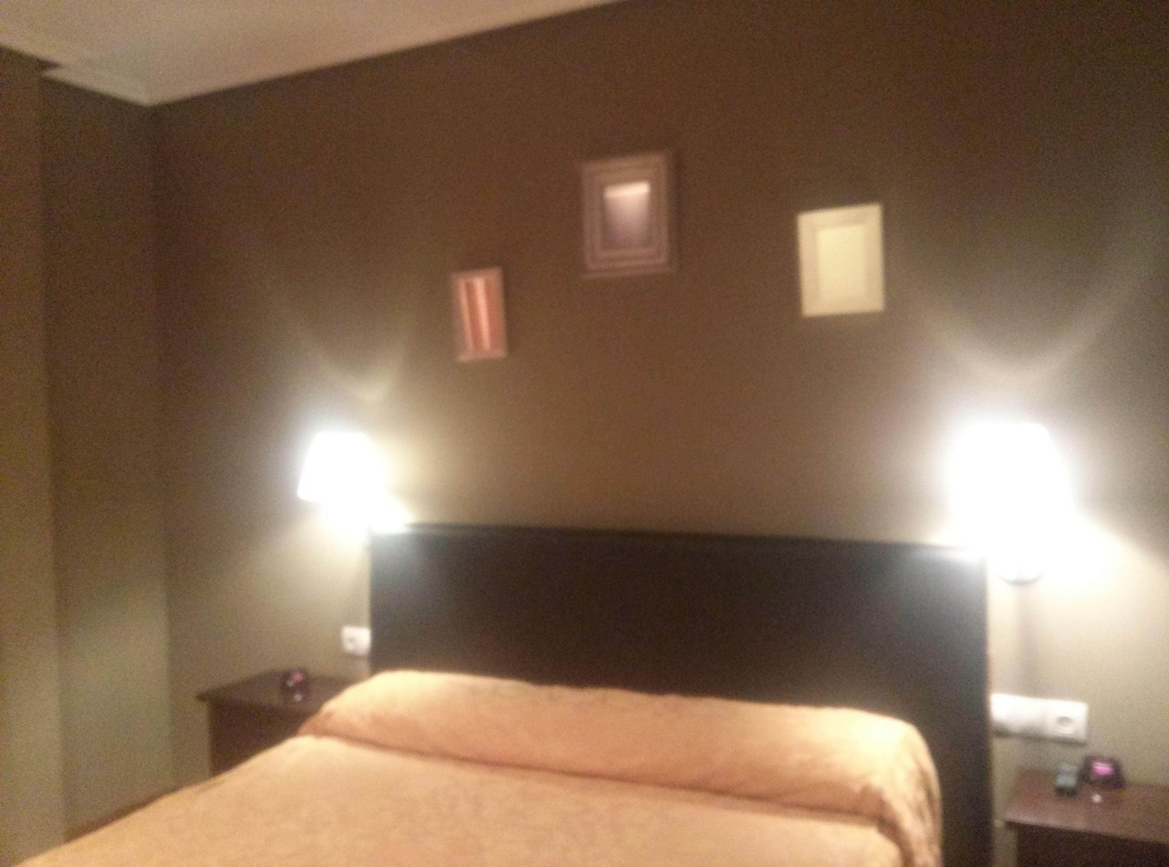 Ein Hotelzimmer mit einem Bett, zwei Nachttischlampen und einem Nachttisch mit Lampe.