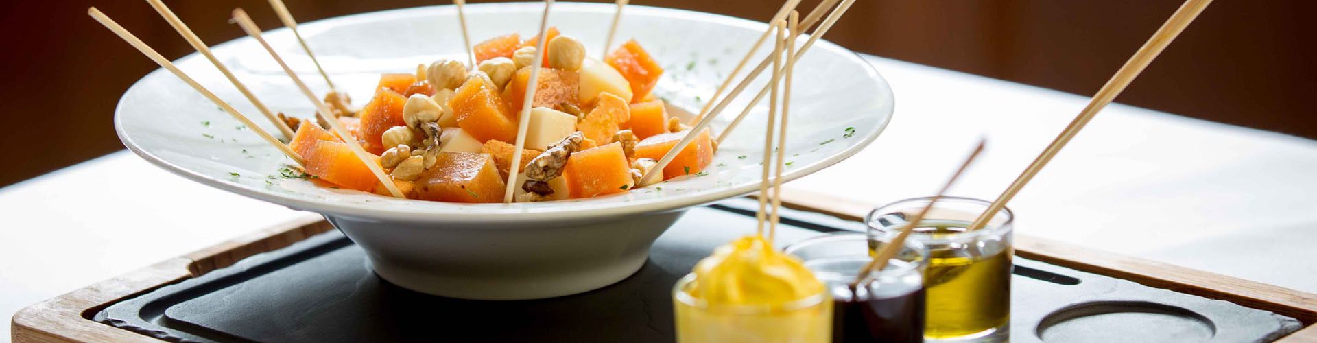 Un tazón de ensalada de frutas con nueces y un frasco pequeño de miel.