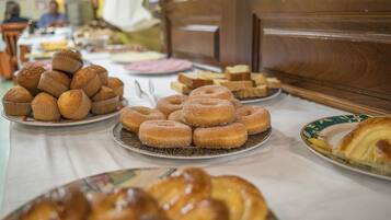 A buffet table with various baked goods including muffins, donuts, and pastries.
