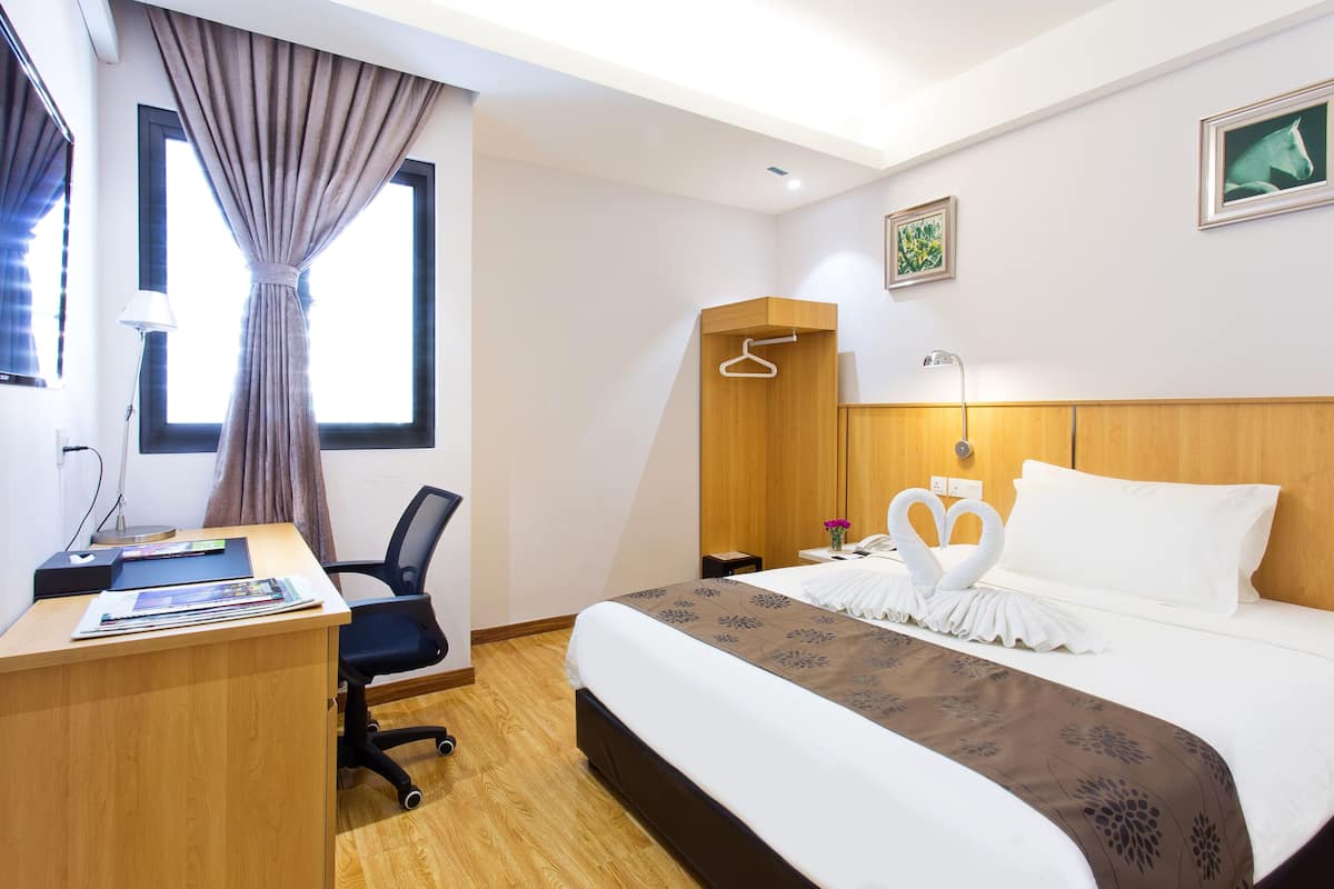 Ein Hotelzimmer mit Bett, Schreibtisch, Stuhl, Kleiderschrank und einem Fenster mit Vorhängen.