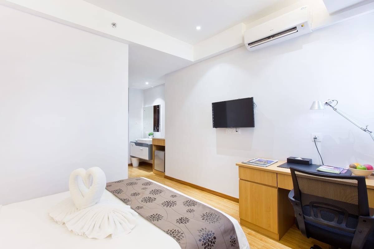 Ein modernes Hotelzimmer mit Bett, Schreibtisch, Stuhl, Fernseher und Schreibtischlampe.