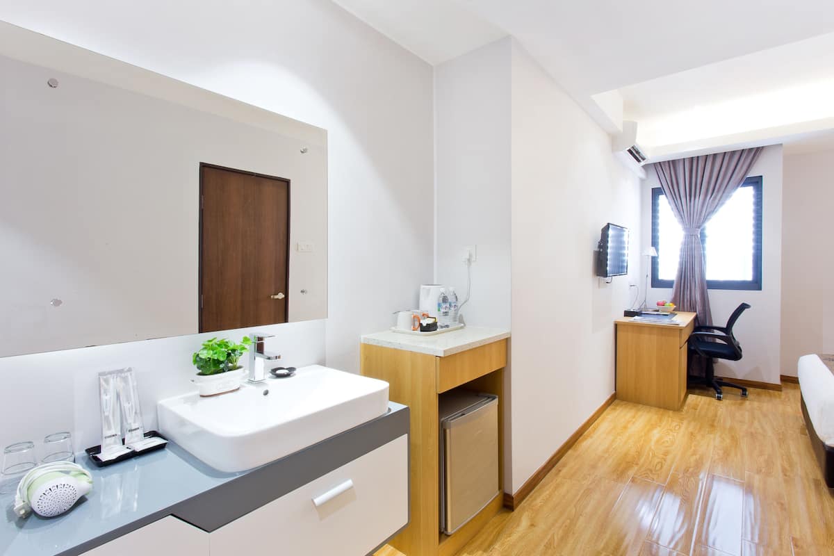 Ein modernes Hotelzimmer mit einem großen Spiegel, einem Holztisch, einer kompakten Küchenzeile und einem Bett.