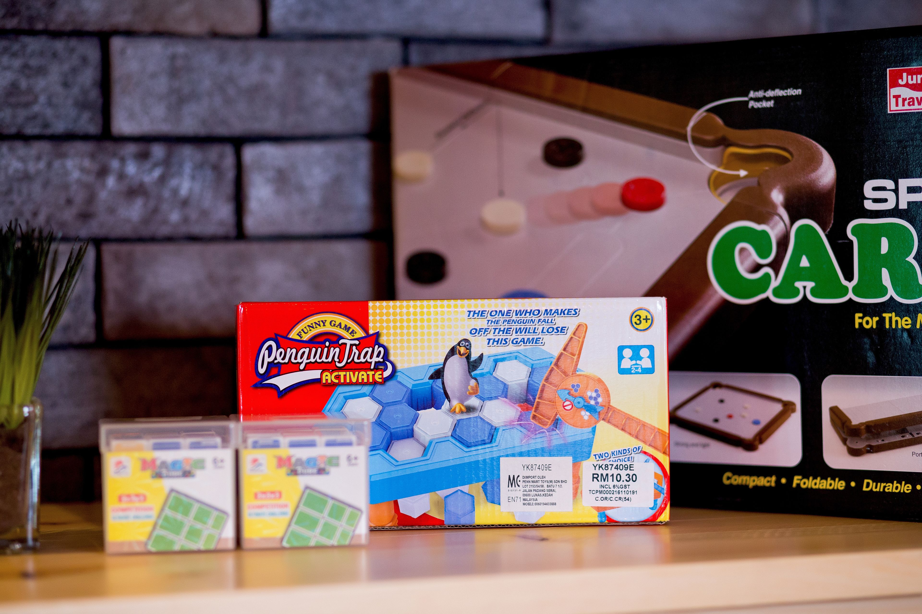 A board game called "Penguin Trap Activate" on a table with a brick wall background.