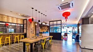 L’intérieur d’un restaurant avec un bar en bois, des chaises jaunes, une longue table à manger et des lanternes rouges.