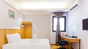 Une chambre d’hôtel avec deux lits, un bureau, une chaise, une télévision et un appareil de climatisation.