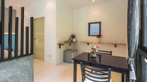 A dining area with a table, chairs, a small cabinet, and a window with curtains. - Modern Resort at Naiyang (Sa Khu)