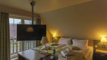 Una camera d'albergo con un letto, lampade sui comodini, una TV a parete, una scrivania con un portatile e una finestra con tende.