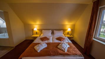 Habitación de hotel con una cama grande, dos mesitas de noche con lámparas, una ventana con cortinas y vistas al exterior.