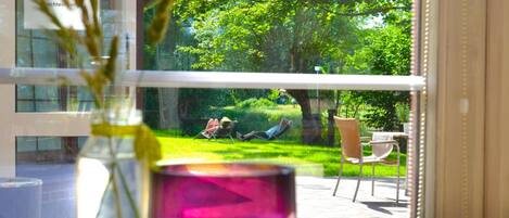 A view from a window overlooking a garden with a lawn and chairs.