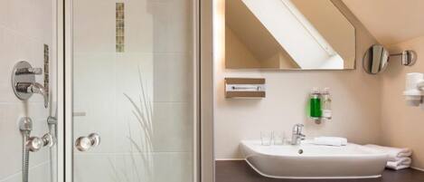 A modern bathroom with a glass shower enclosure, a white sink, and a mirror above it.