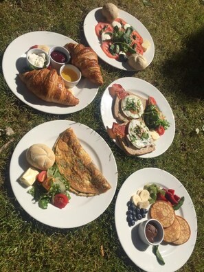 A picnic setup with plates of food including croissants, eggs, and vegetables on a grassy area. - Imperial Apartments - Nadmorski (Sopot)