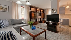Una sala de estar moderna con sofá, mesa de centro, televisor y zona de cocina.