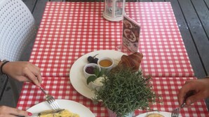 Una mesa con mantel a cuadros rojo y blanco, dos platos de comida, una planta pequeña en maceta y un farol.