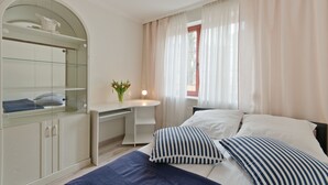 Un dormitorio con cama, mesita de noche y escritorio con silla.