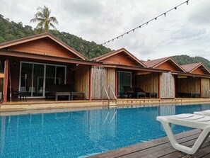 A poolside area with a wooden deck, lounge chairs, and a clear blue pool. - Lanta For Rest Boutique (Ko Lanta)