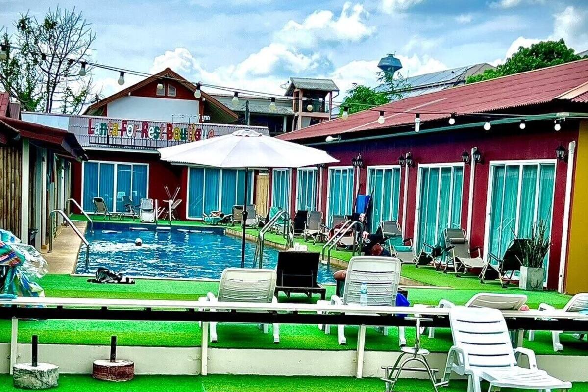 A pool area with lounge chairs, a small pool, and a building with a sign.
