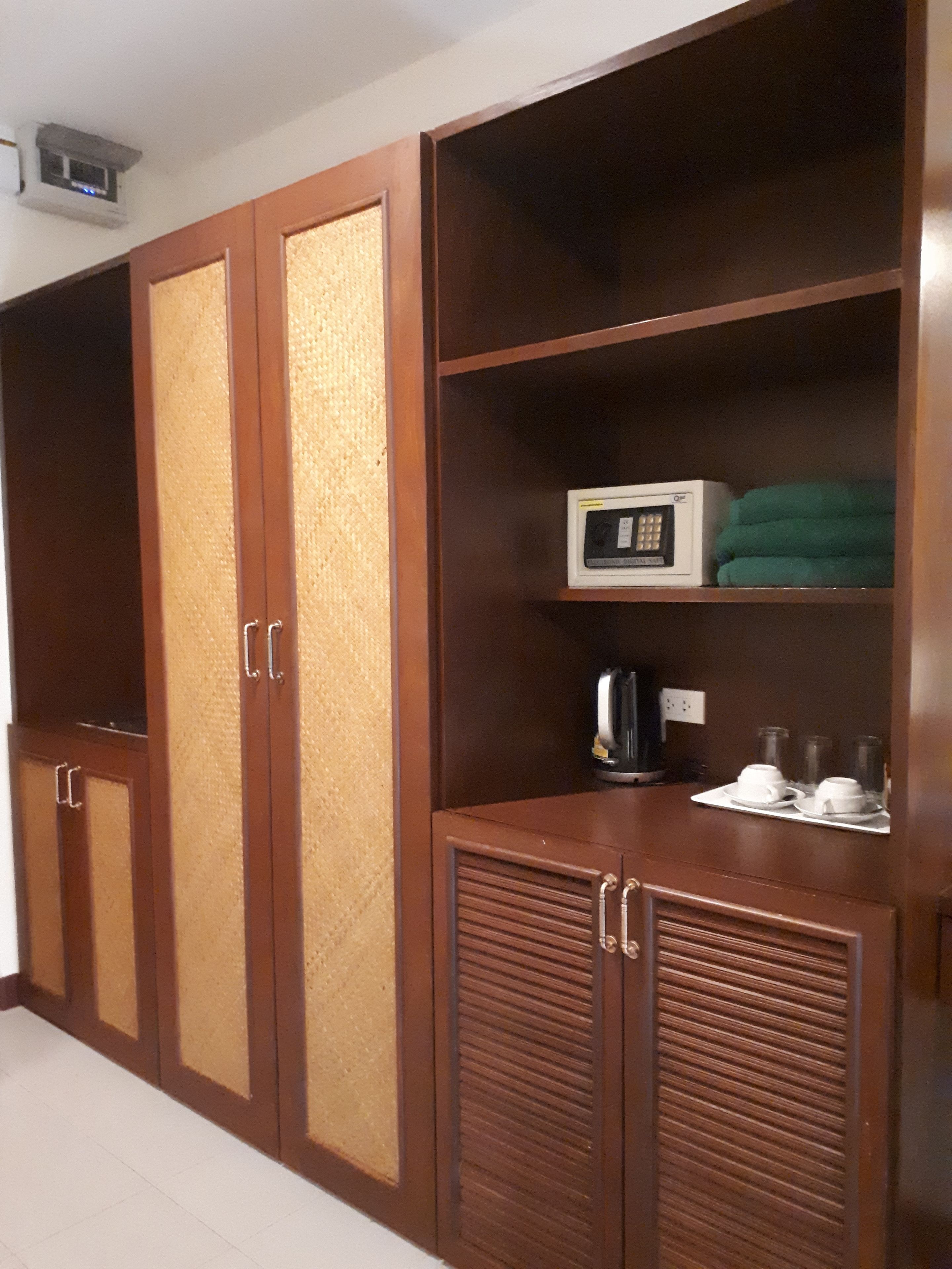A wardrobe with multiple compartments, a microwave, and a tray with cups and a kettle.