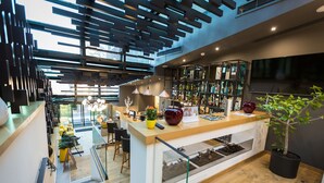Un área de bar moderna con mostrador de madera, asientos y una gran pantalla de televisión.