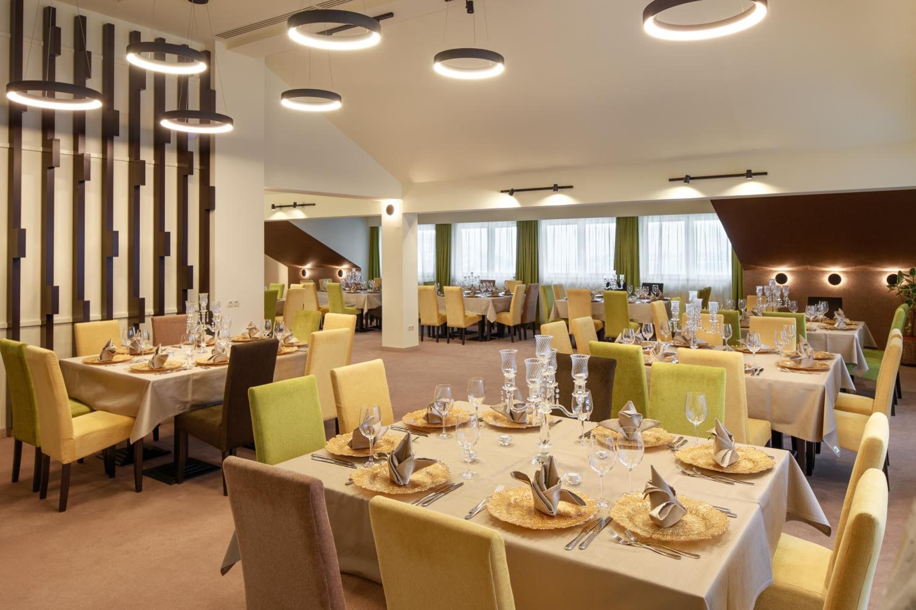 A restaurant with multiple tables set for dining, featuring a modern interior with vertical wooden panels and recessed lighting.