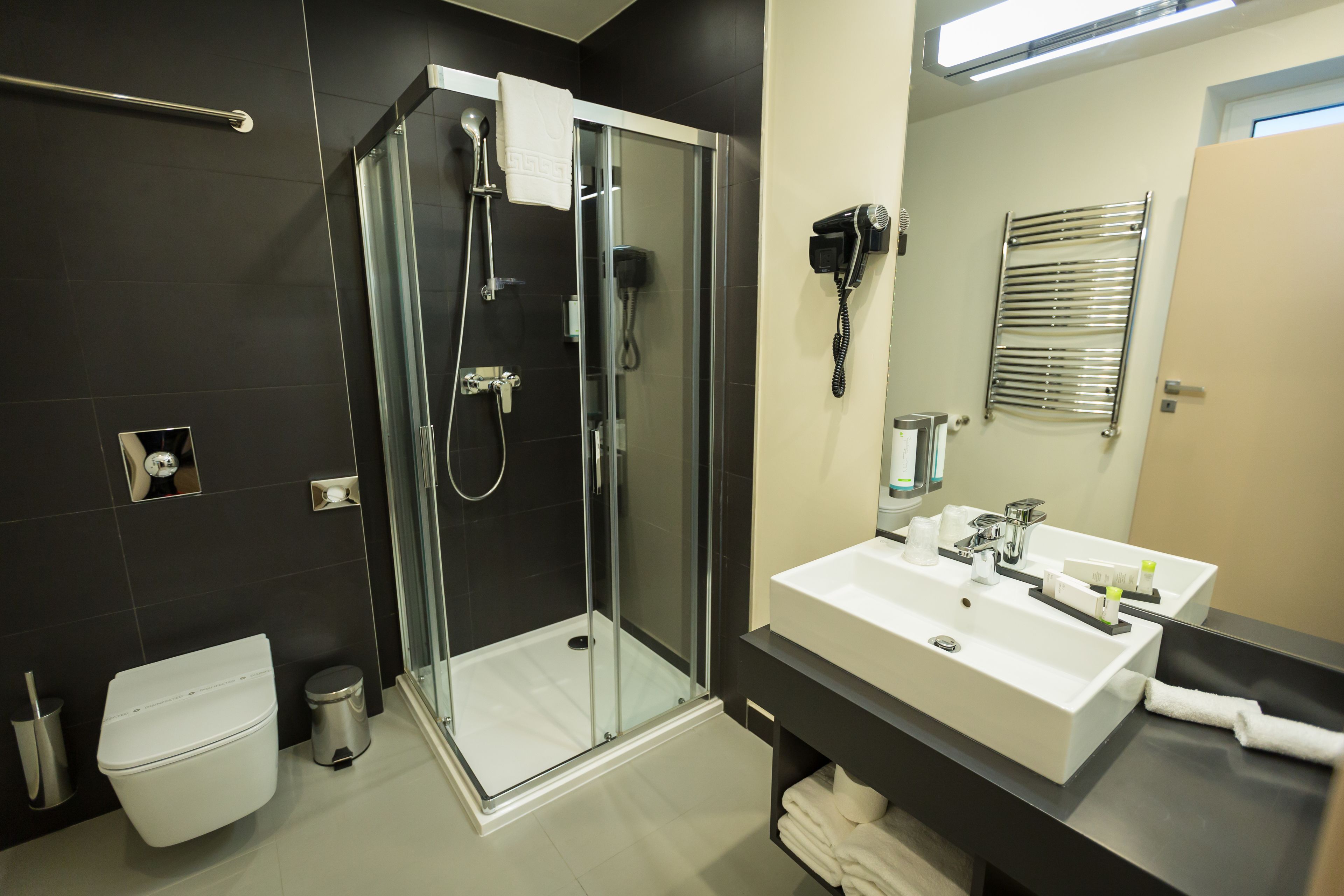 A modern bathroom with a glass-enclosed shower, a white sink, and a black vanity.