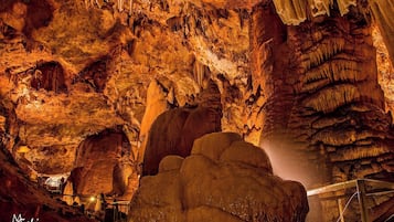 Una cueva con estalactitas y estalagmitas, un pasillo de metal y una gran formación rocosa.
