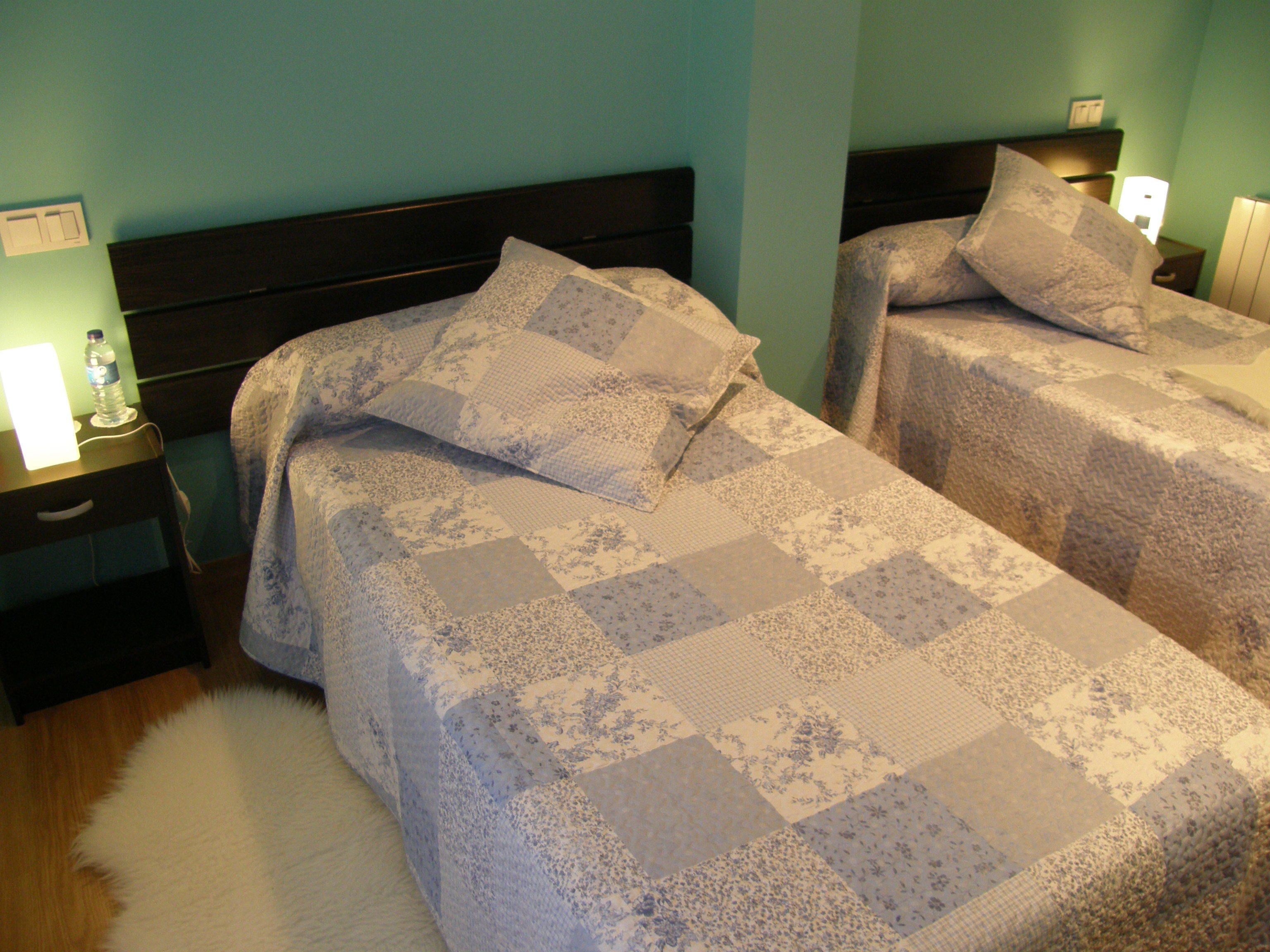 Une chambre double avec deux lits, chacun doté d’une tête de lit, de tables de chevet et de lampes.