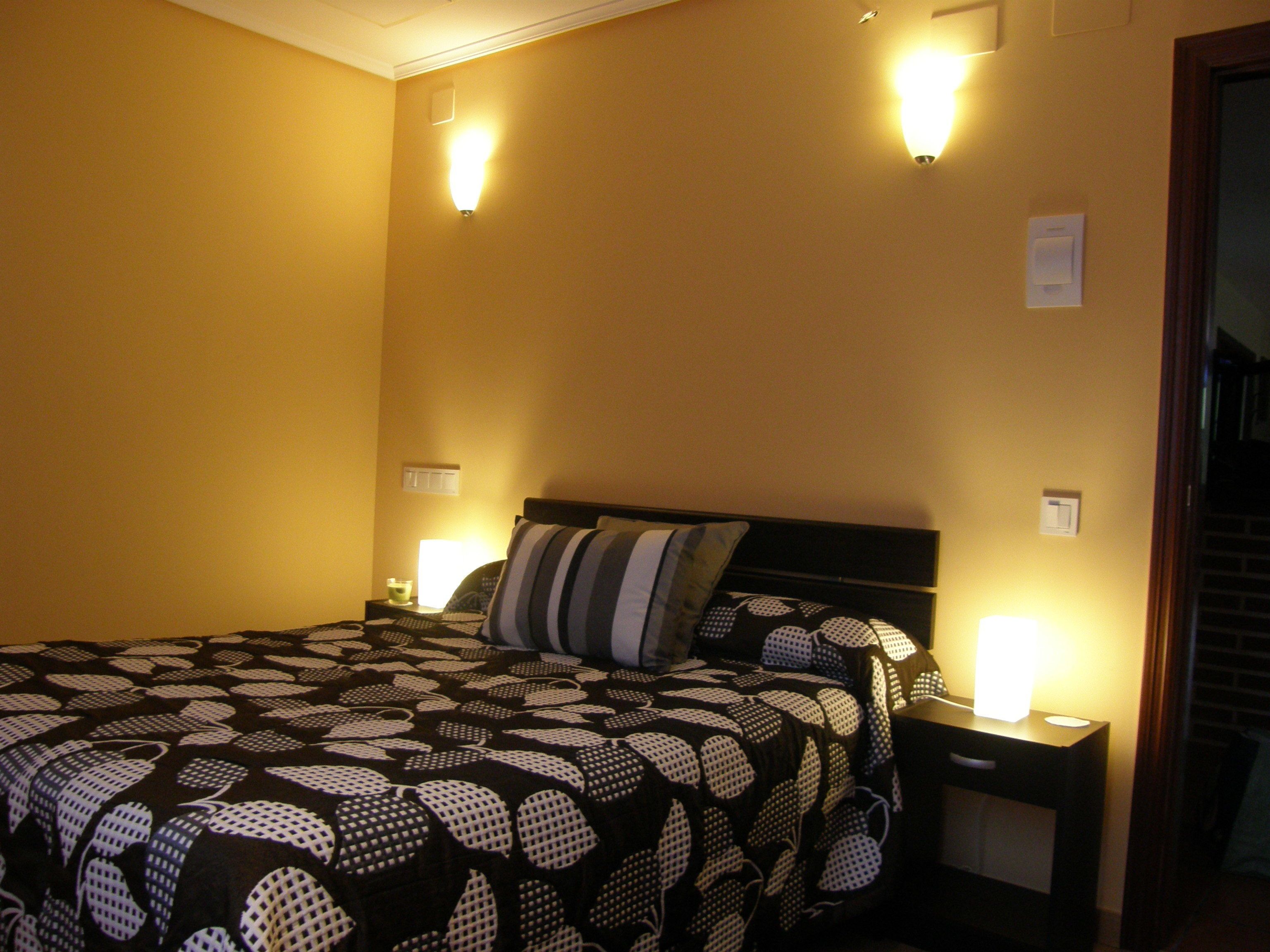 A hotel room with a bed, two bedside lamps, and a nightstand.