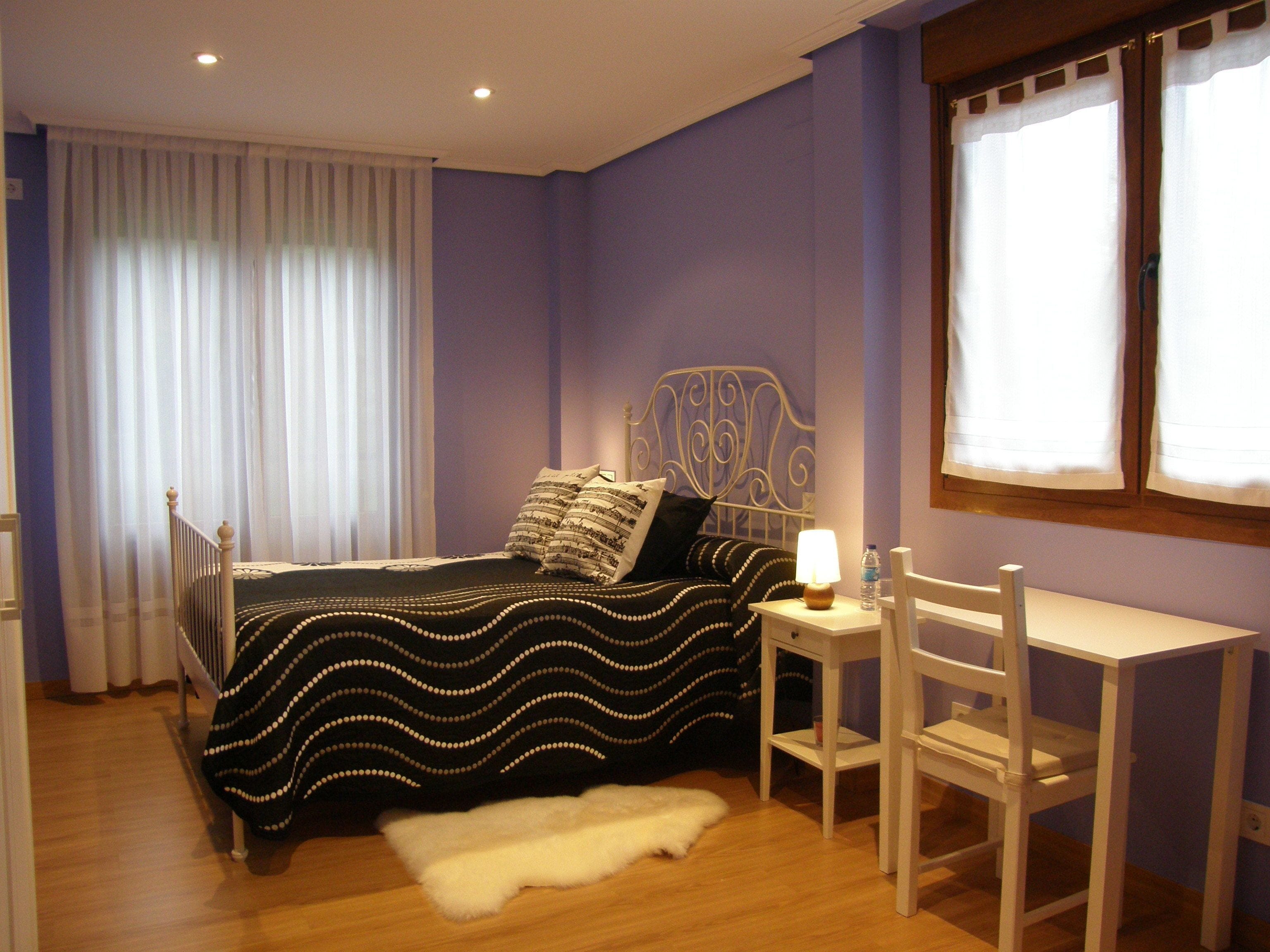 A bedroom with a bed, a desk, and a chair.