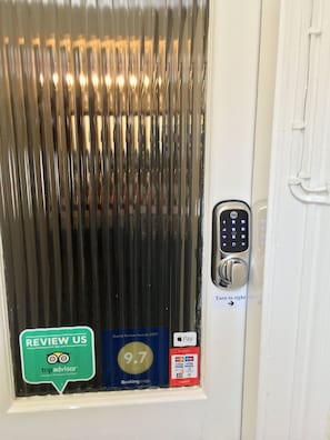 A door with a vertical striped pattern, a Yale electronic lock, and a TripAdvisor badge indicating a 9.7 rating. - Belford House (Haltwhistle)