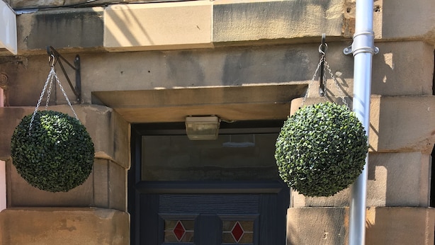 A dark wooden door with a sign reading "Belford House" above it.