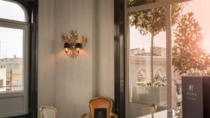 Une pièce dotée d’une grande fenêtre, d’un lustre, d’une table et de deux chaises.