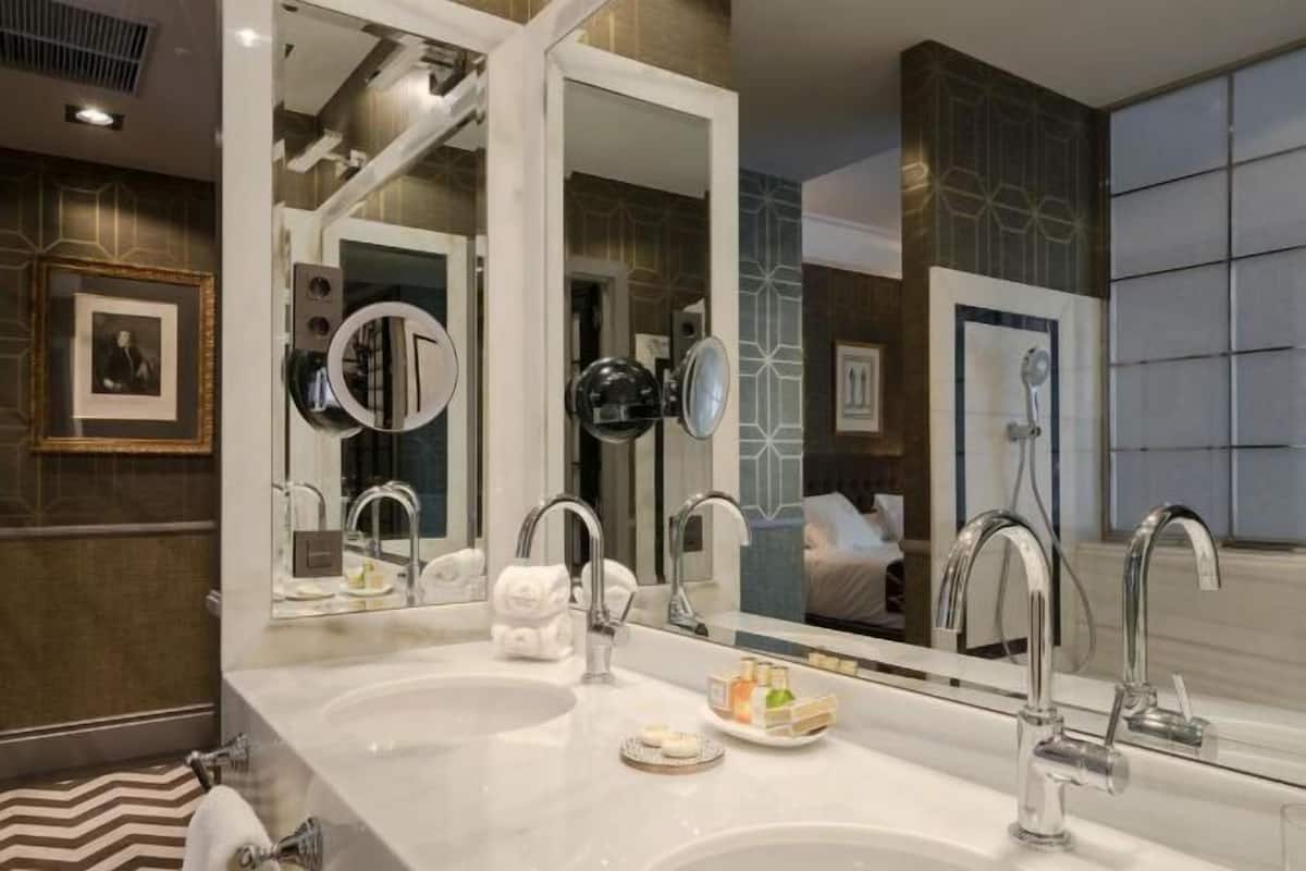 Een moderne badkamer met twee wastafels, een grote spiegel en een douche.