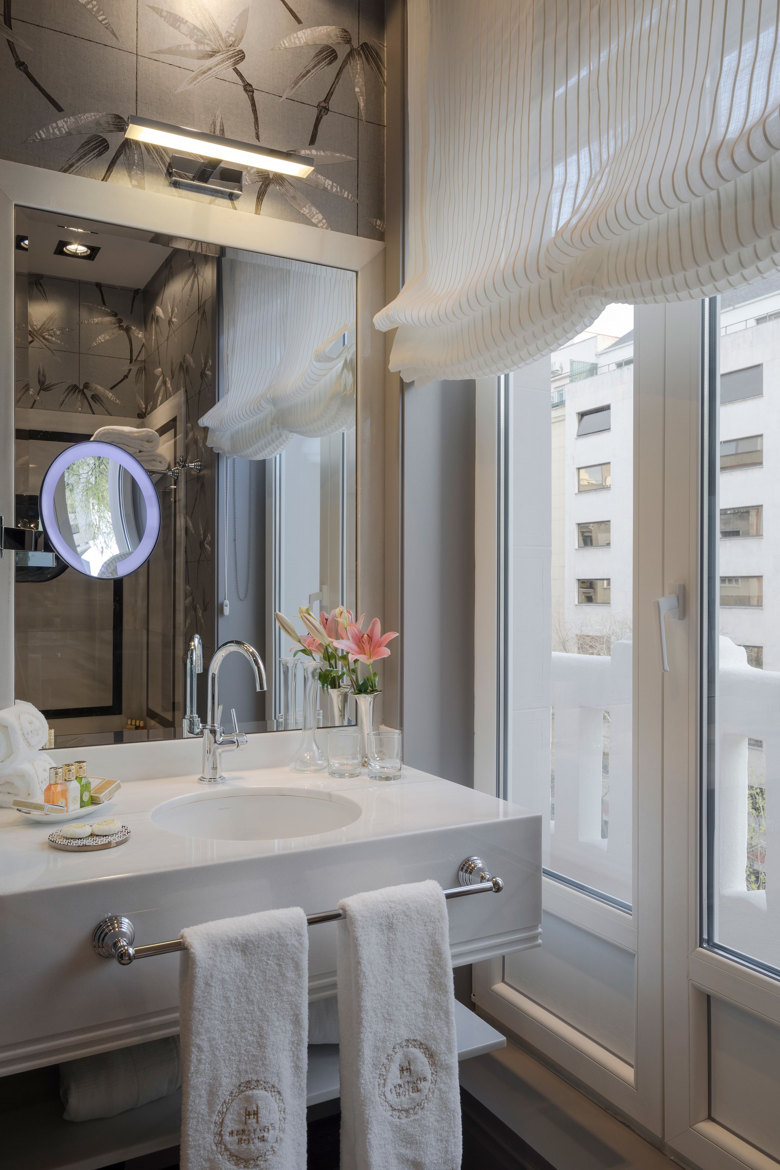 Un baño moderno con un espejo grande, un lavabo y una ventana.