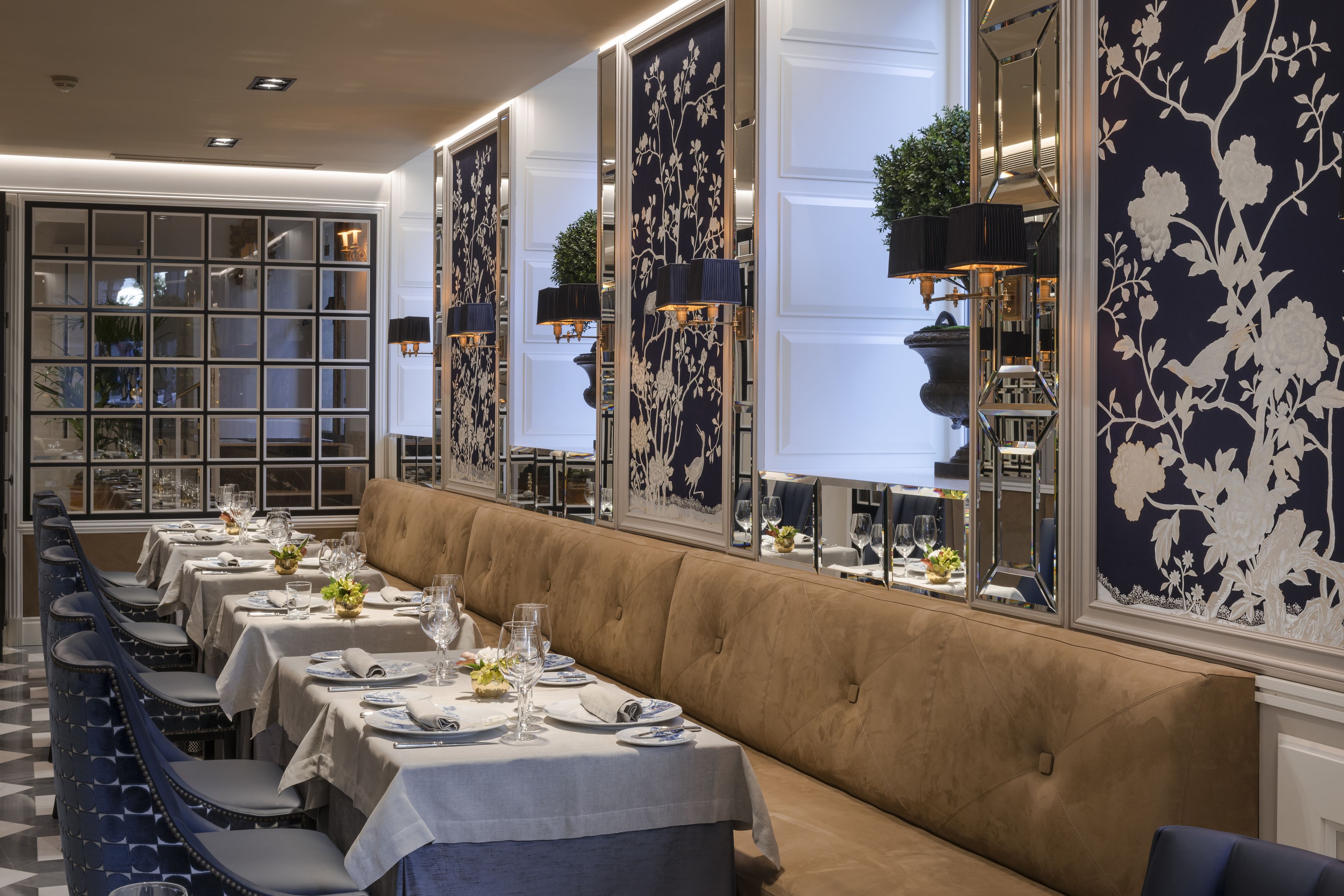 A long dining table with multiple chairs, a cushioned bench, and a large window with decorative panels.