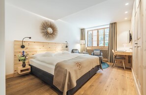 Quarto moderno com cabeceira de madeira, cama grande, escrivaninha e janela com cortinas.
