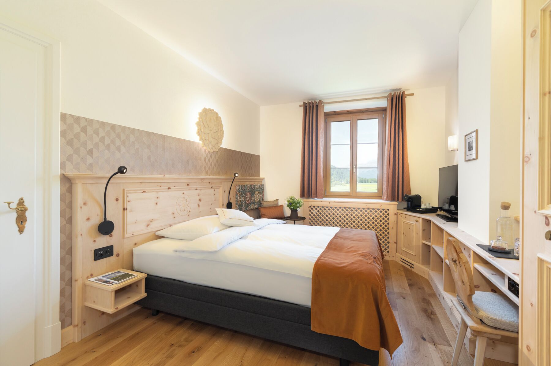Une chambre à coucher comprenant un lit, une table de chevet, une lampe, une fenêtre avec des rideaux et un bureau avec une chaise.