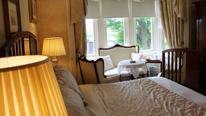A hotel room with a bed, a chair, a small table, and a window with curtains. - Innisfree House (Dundalk)