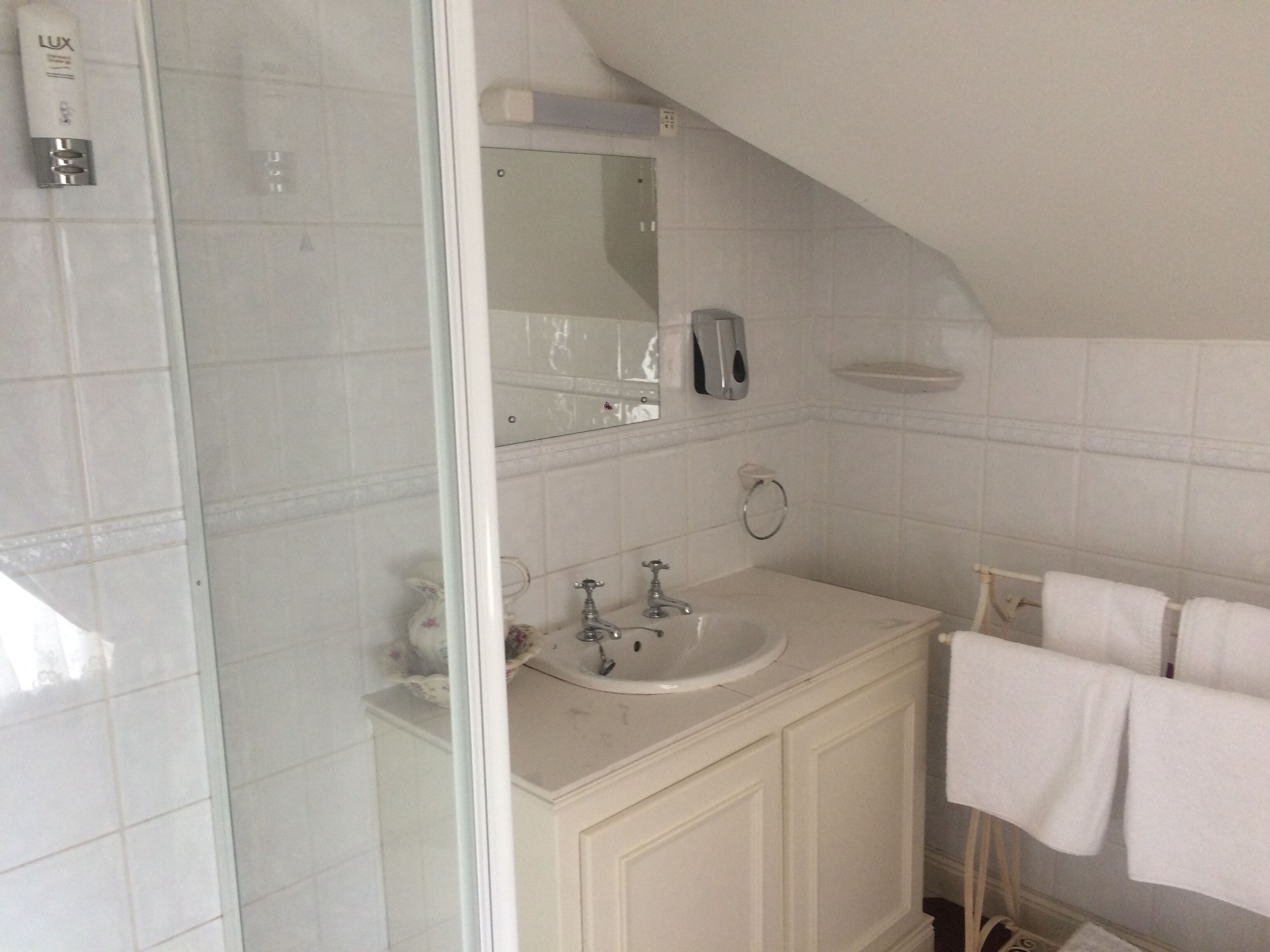 A bathroom with a white sink, mirror, and towel rack.