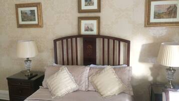 A neatly made bed with a wooden headboard, two bedside tables with lamps, and three framed pictures on the wall.